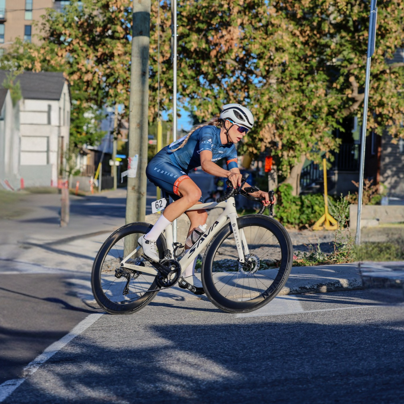 Cyclist riding a bicycle on a street with buildings and trees in the background